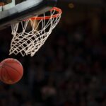 Basketball passing through net, crowd in the background