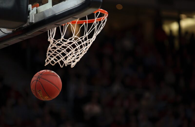 Basketball passing through net, crowd in the background